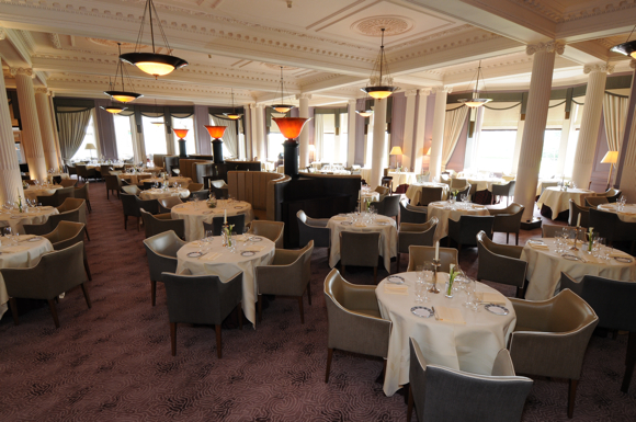 The refurbished main dining room of the Strathearn features a color scheme of cream, taupe, rose and burgundy; curved banquettes providing discreet dining areas in the center of the room; and an enhanced lighting scheme.