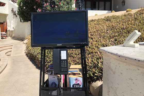 A computer screen attached to a small lending library at the Las Ventanas al Paraiso, A Rosewood Resort, shows a short video of residences for sale.