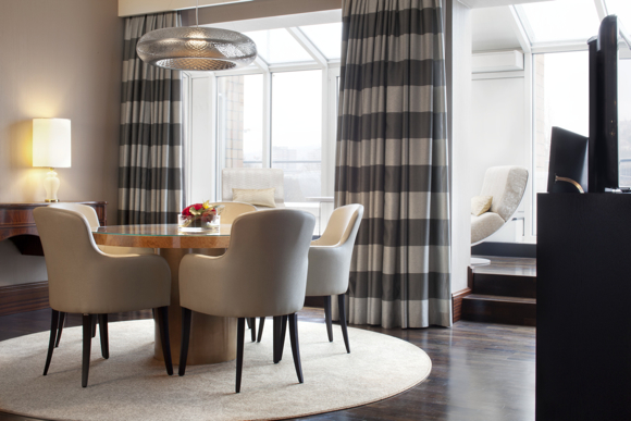 The area adjacent to the Presidential Suite’s living room offers a round dining table and a solarium fitted with ivory upholstered loungers.